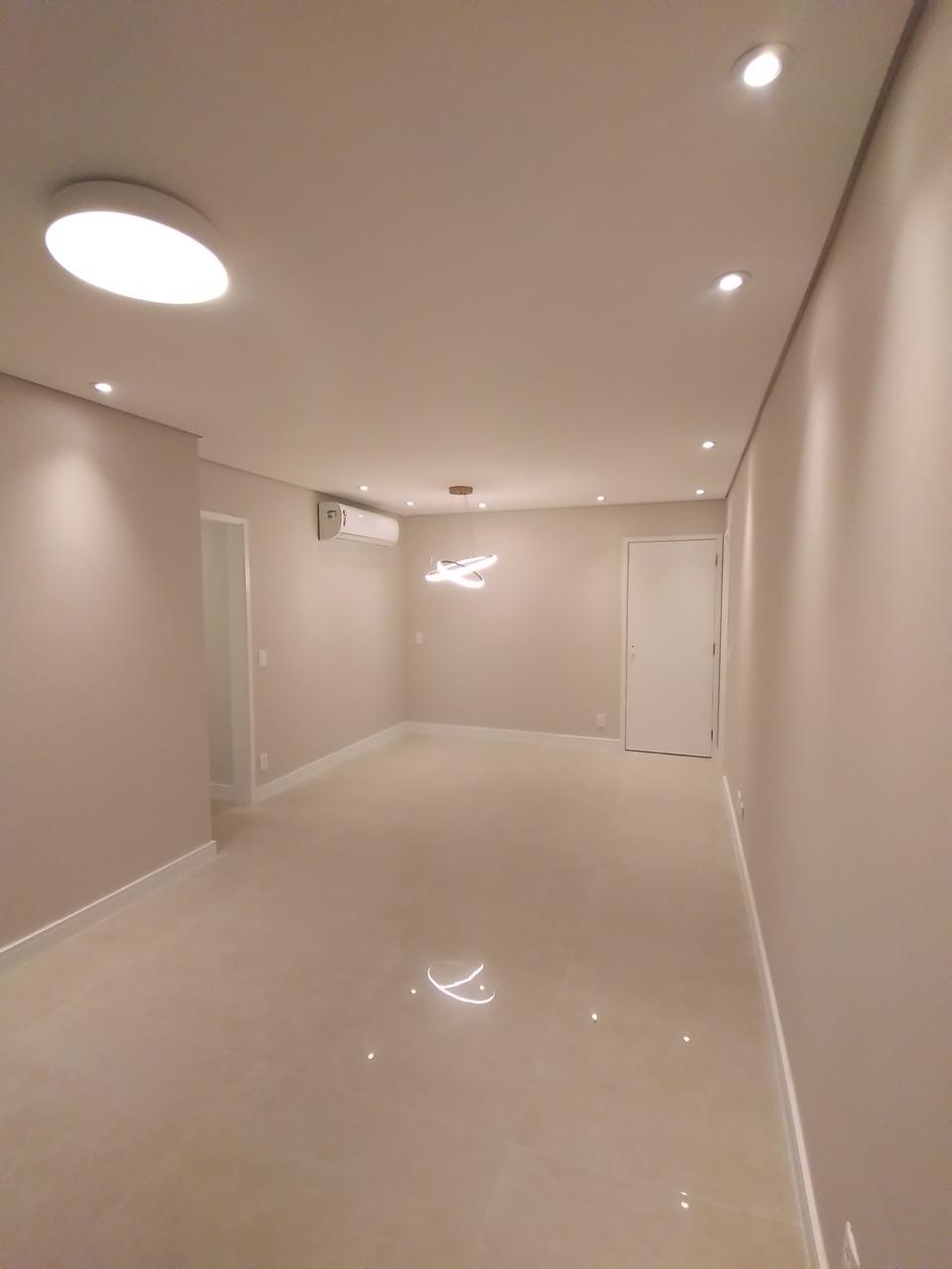 Interior residencial de alto padrão com piso porcelanato polido, paredes em tom neutro, iluminação embutida e ar-condicionado split.