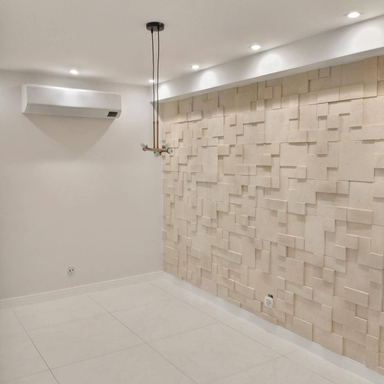 Ambiente interno entregue com parede de revestimento 3D em pedra natural, piso porcelanato, iluminação embutida em gesso e ar-condicionado split.