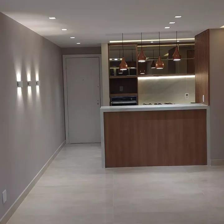 Cozinha de alto padrão concluída com ilha em mármore branco, iluminação LED embutida, pendentes de design e painel ripado em madeira.