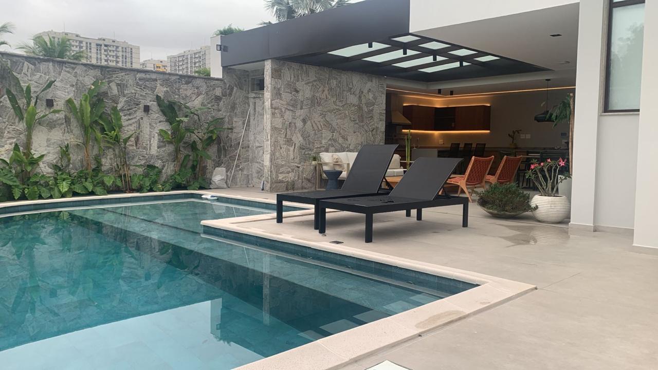 Área de lazer com piscina, revestimento em pedra natural, espreguiçadeiras e espaço gourmet integrado, exemplo de acabamento premium entregue.