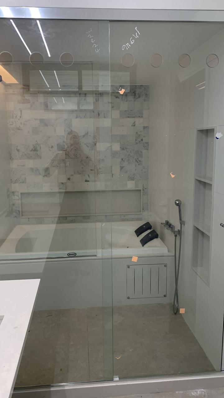 Banheiro de alto padrão com revestimento em mármore, banheira com nichos, box de vidro e acabamento premium.